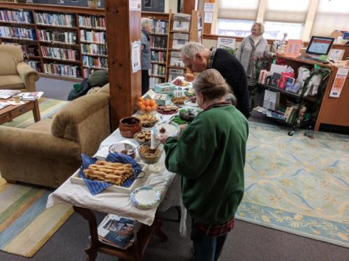 CommuniTEA attendees choosing delicious treats from food table at December 2017 CommuniTEA